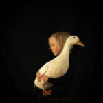Photography of young girl holding a duck
