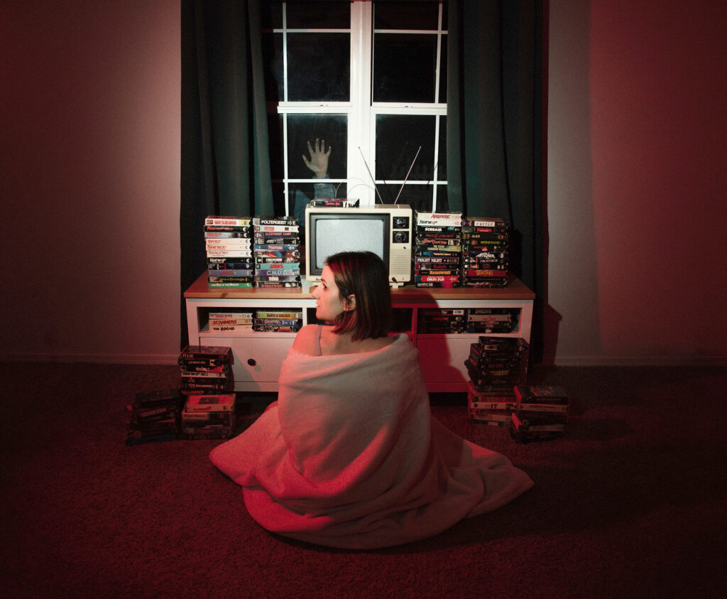 WHAT A FEELING Self Portrait (2021) by Mitzi Starkweather. Woman sitting in the floor in front of a TV.